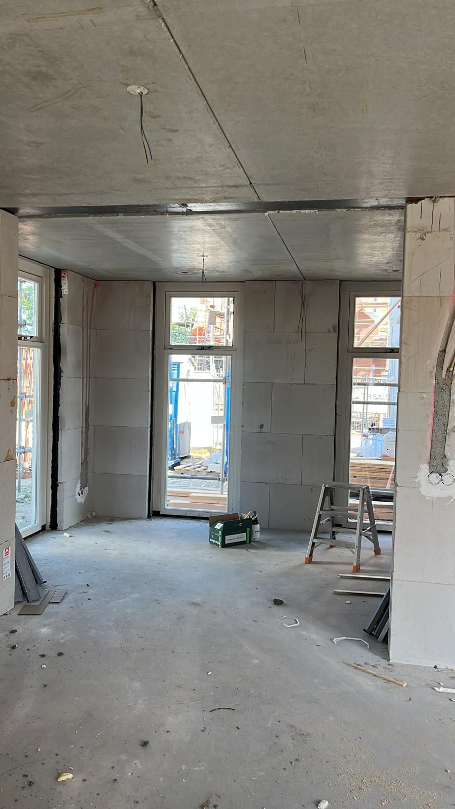 Ruwbouw interieur met een hoge glazen deur en ramen aan het eind van de ruimte