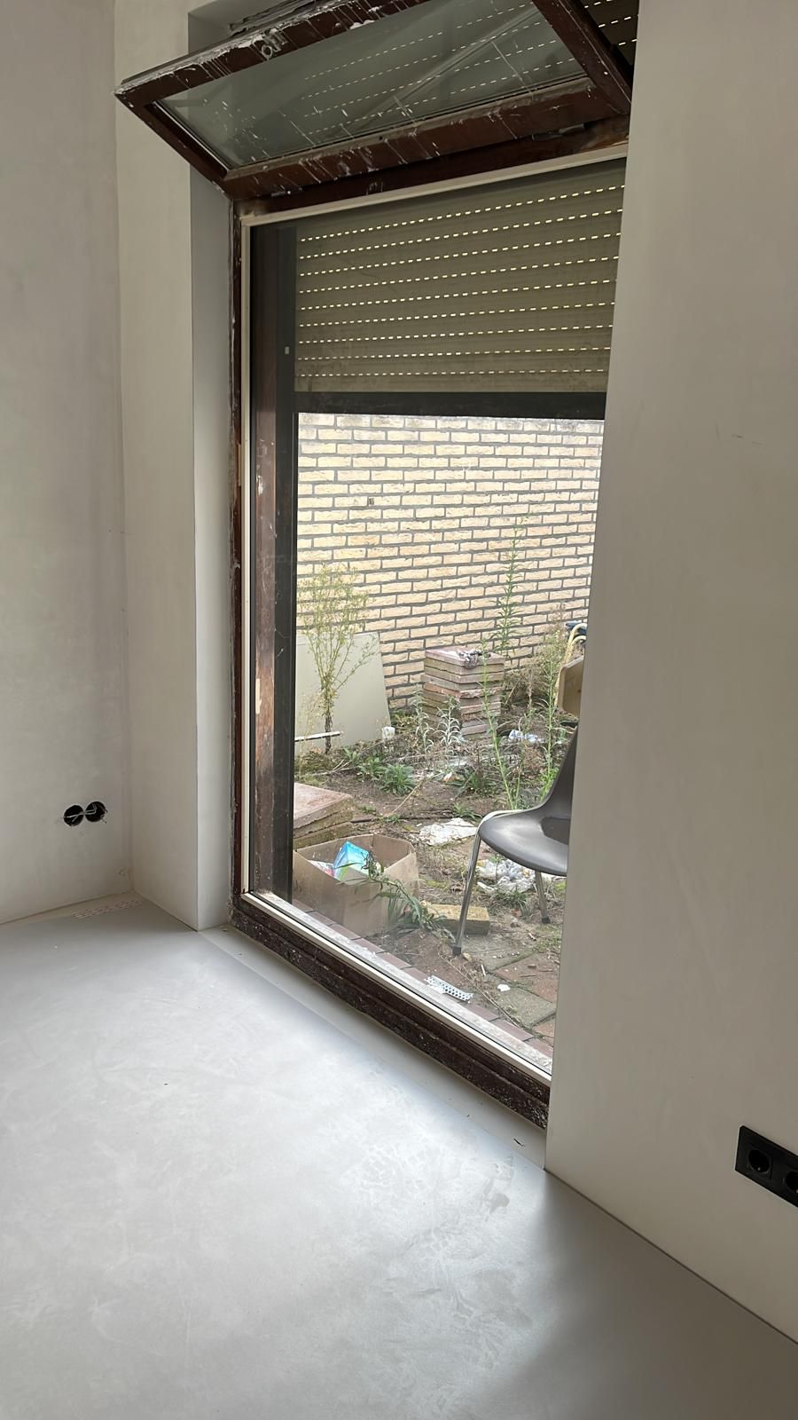Groot nieuw raam met kiepraam en rolluik in een net gestucte kamer