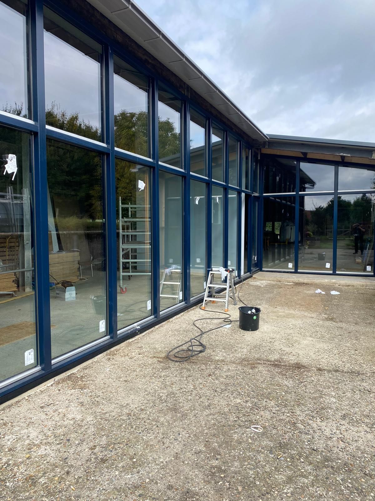 Lange glazen gevel met donkerblauwe kozijnen van een paviljoen