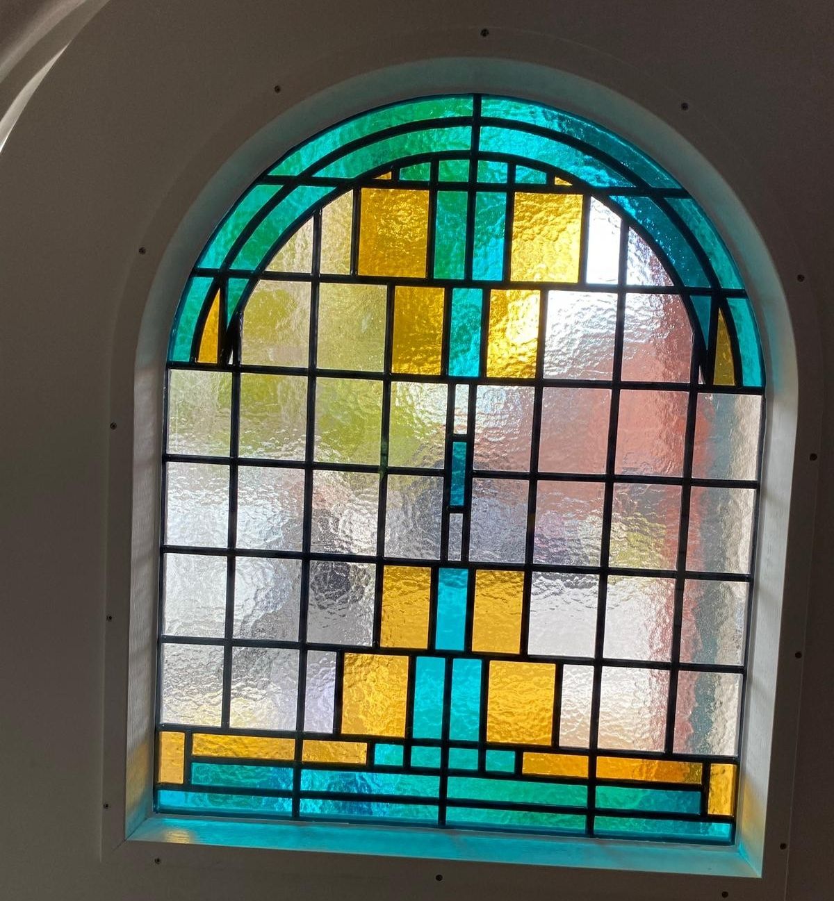 Boogvormig glas-in-lood raam in turquoise, amber en helder structuurglas