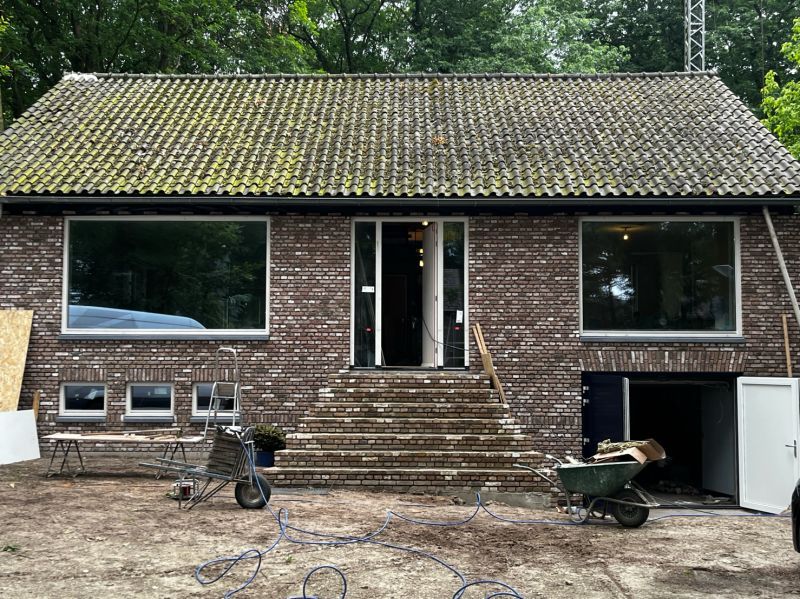 Gerenoveerde bakstenen woning met grote nieuwe ramen en glazen deuren aan de voorzijde