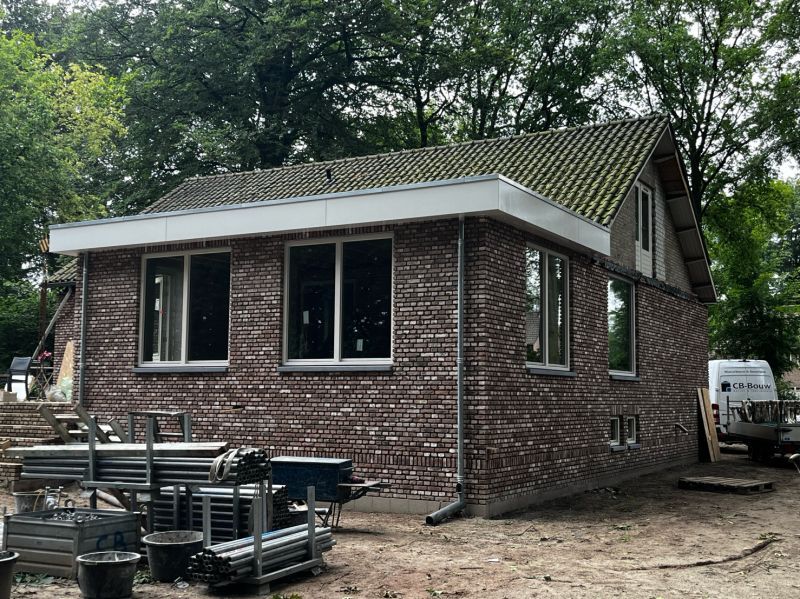Zijgevel van dezelfde woning met nieuwe ramen tijdens de afronding van de verbouwing